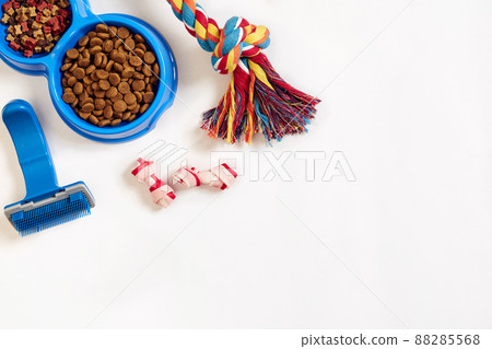 Dog care items, isolated on white background. Dry pet food in bowl, toy and bones. Top view Dog care items, isolated on white background. Dry pet food in bowl, toy and bones. Top view 88285568