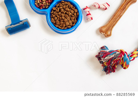Dog care items, isolated on white background. Dry pet food in bowl, toy and bones. Top view 88285569