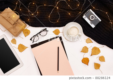 Romantic autumn mock up. Sheet of pink paper, yellow and orange leaves, pencils, cup of cappuccino and old camera.Top view. Flat lay. 88286124