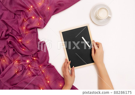 Top view of girl's hand writing on small black wooden board on white surface with coffee cup and other items. Mock up Top view of girl's hand writing on small black wooden board on white surface with coffee cup and other items. Mock up 88286175