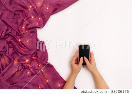 Mockup image of woman's hand holding mobile phone with blank screen on white background with scarf in modern cafe Mockup image of woman's hand holding mobile phone with blank screen on white background with scarf in modern cafe 88286176