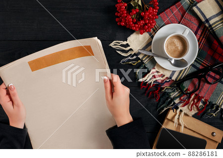 Smartphone and coffee cup, reading glasses, notebook, hands holding newspaper. Smartphone and coffee cup, reading glasses, notebook, hands holding newspaper. 88286181