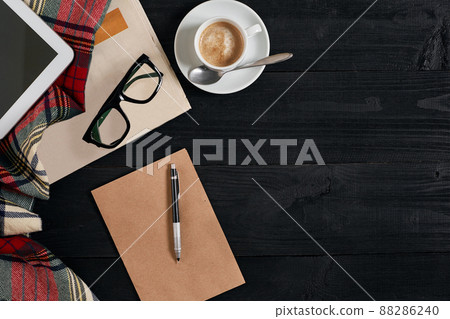 Workspace with newspaper, coffee cup, scarf, glasses. Stylish office desk. Autumn or Winter concept. Flat lay, top view Workspace with newspaper, coffee cup, scarf, glasses. Stylish office desk. Autumn or Winter concept. Flat lay, top view 88286240