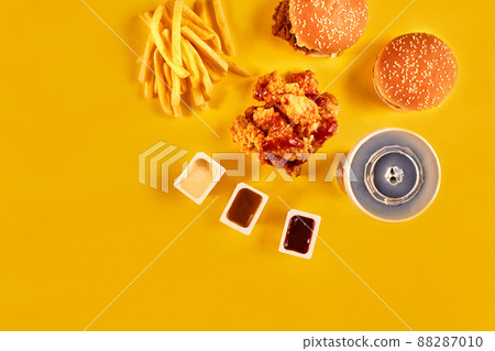 Fast food dish top view. French fries, hamburger, mayonnaise and ketchup sauces on yellow background. Fast food dish top view. French fries, hamburger, mayonnaise and ketchup sauces on yellow background. 88287010