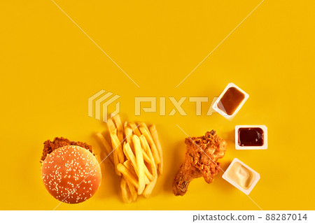 Fast food dish top view. French fries, hamburger, mayonnaise and ketchup sauces on yellow background. Fast food dish top view. French fries, hamburger, mayonnaise and ketchup sauces on yellow background. 88287014