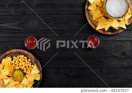 Lager beer and snacks on black wooden table. Nuts, chips. Top view with copyspace Lager beer and snacks on black wooden table. Nuts, chips. Top view with copyspace 88287077