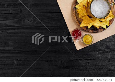 Glass of beer with nachos chips on a wooden background. 88287084