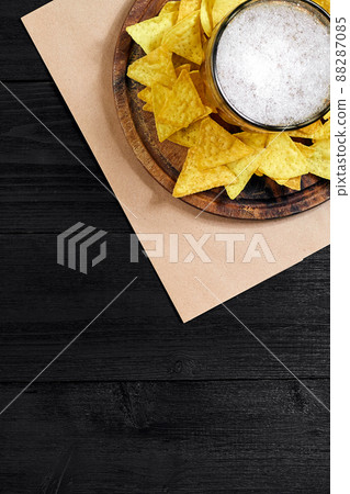 Glass of beer with nachos chips on a wooden background. Glass of beer with nachos chips on a wooden background. 88287085