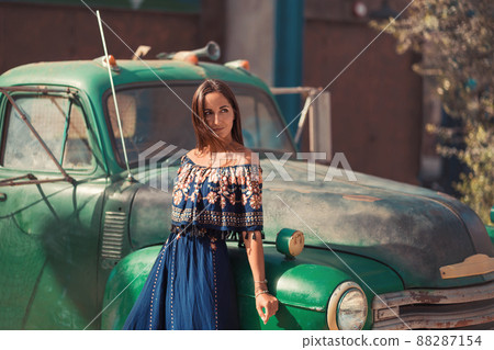 Beautiful young woman posing near green vintage car Beautiful young woman posing near green vintage car 88287154