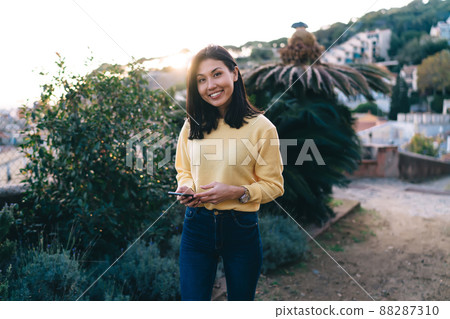 Happy Asian tourist with smartphone technology smiling at camera during time for walking 88287310