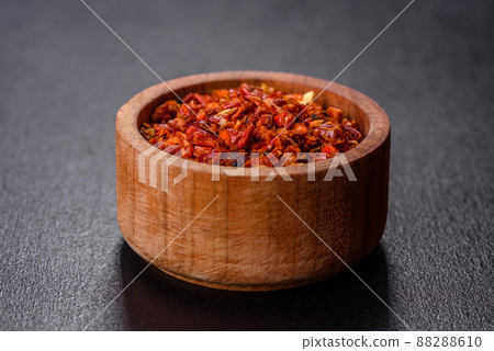 Red crushed paprika in a wooden dish on a dark concrete background 88288610