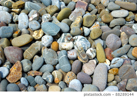 sea pebble beach with multicoloured stones, transparent waves with foam, on a warm summer day 88289144