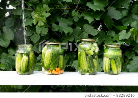 Four cans of fresh cucumbers are filled with boiled marinade for preservation. Four cans of fresh cucumbers are filled with boiled marinade for preservation. 88289216