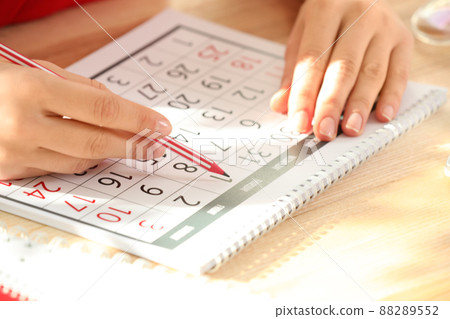 Woman marking date in calendar at wooden table, closeup Woman marking date in calendar at wooden table, closeup 88289552