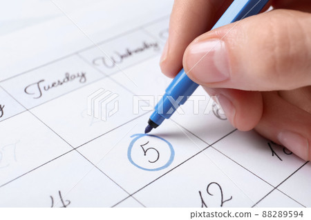Woman marking date in calendar with felt pen, closeup 88289594