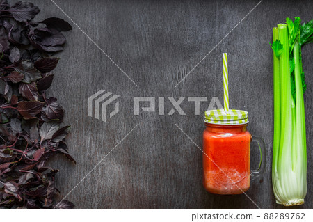 Spicy tomato drink with celery and basil. Tomato drink in jar surrounded of fresh vegetables on a wooden table 88289762