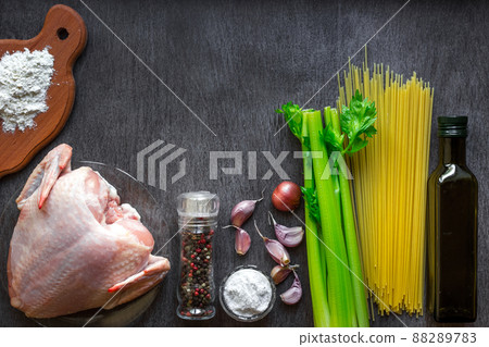 Pasta ingredients. Chicken breasts, oil, spaghetti pasta, elery, spices and garlic on the wooden table. Space for text. 88289783