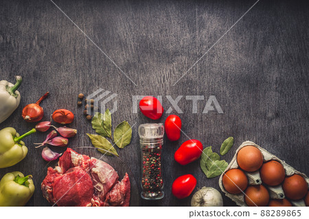 Raw pork meat on a dark wooden surface and ingredients for cooking. Food background with copy space. 88289865