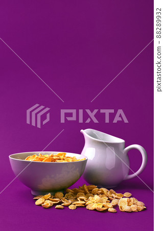 Bowl with corn flakes, jug of milk on purple background. oncept of a healthy breakfast Bowl with corn flakes, jug of milk on purple background. oncept of a healthy breakfast 88289932