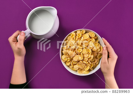Food and people concept - hands of woman eating cereals corn flakes for breakfast and pouring milk Food and people concept - hands of woman eating cereals corn flakes for breakfast and pouring milk 88289963