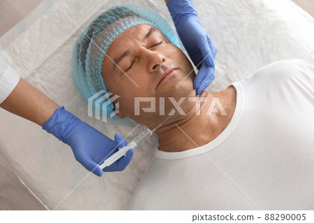 Mature man with double chin receiving injection in clinic, above view Mature man with double chin receiving injection in clinic, above view 88290005
