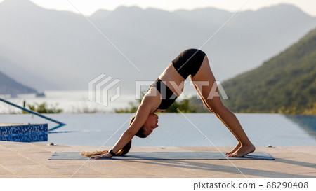 Young woman doing vinyasa yoga routine in the morning at the resort pool 88290408