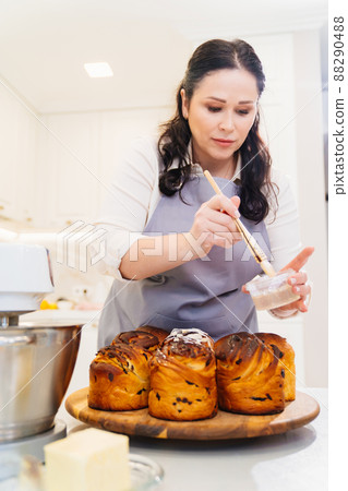 a female cook lubricates with melted butter a Kraffin, easter cake a female cook lubricates with melted butter a Kraffin, easter cake 88290488