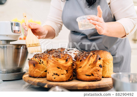 a female cook lubricates with melted butter a Kraffin, easter cake a female cook lubricates with melted butter a Kraffin, easter cake 88290492