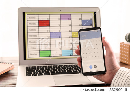 Woman holding smartphone with calendar app at table, closeup 88290646