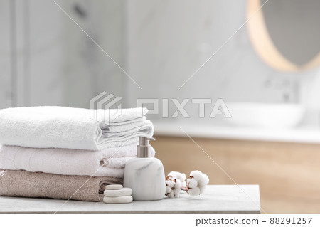 Clean towels, spa stones and soap dispenser on table in bathroom. Space for text 88291257