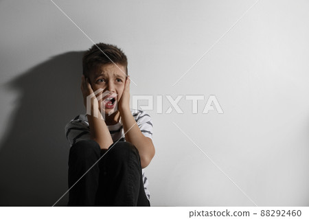 Scared little boy closing his ears near white wall, space for text. Domestic violence concept 88292460