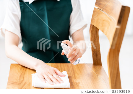 一名穿著圍裙為椅子消毒的婦女的手 [零件切割] 88293919