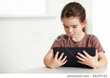 Digital age for all ages. Shot of an adorable little girl reading a digital tablet. Digital age for all ages. Shot of an adorable little girl reading a digital tablet. 88297183