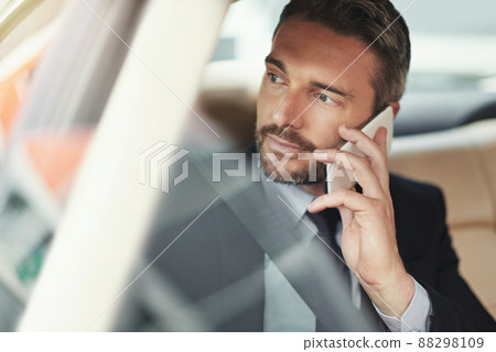 Staying connected in commute. Shot of a businessman using his phone while traveling in a car. Staying connected in commute. Shot of a businessman using his phone while traveling in a car. 88298109