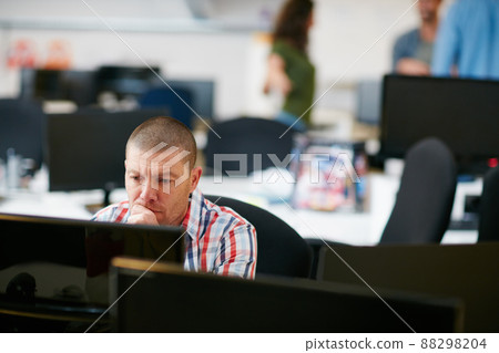 He knows the importance of hard work. Shot of a man using a computer in a modern office. He knows the importance of hard work. Shot of a man using a computer in a modern office. 88298204