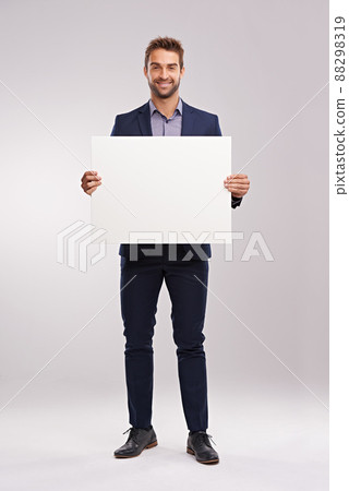 Have I got news for you. Studio shot of a handsome man in a suit holding up a blank sign. 88298319
