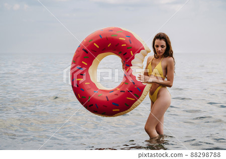 slender woman with a sexy body in a swimsuit with an inflatable circle in her hands is resting on the sea 88298788
