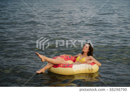 slender girl swims on an inflatable circle in the sea in summer slender girl swims on an inflatable circle in the sea in summer 88298790