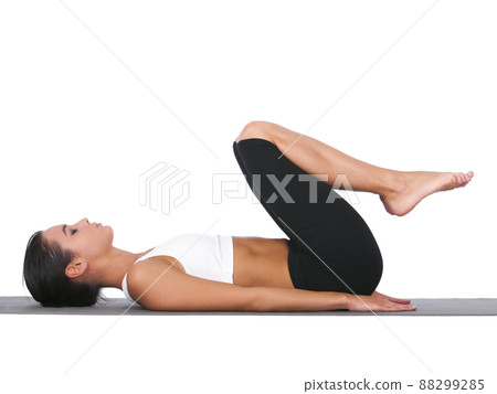 Holding her core in tightly. A young woman doing stretches while isolated on white. 88299285