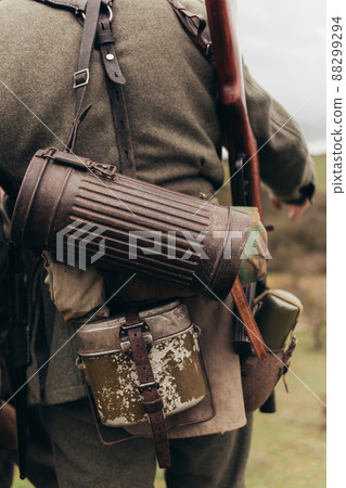 A man in a soldier's uniform with a flask and a tube during the reconstruction of hostilities 88299294