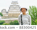 Happy Asian woman smiling with Himeji castle background. A female tourist is smiling and looking at camera in casually standing outdoor on a spring day. 88300425