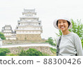 Happy Asian woman smiling with Himeji castle background. A female tourist is smiling and looking at camera in casually standing outdoor on a spring day. 88300426