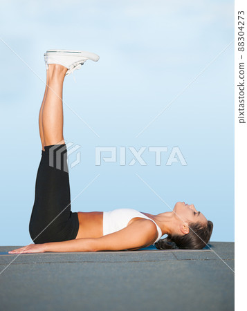 Stretching those hamstrings. A young woman doing yoga outdoors against a blue sky. 88304273