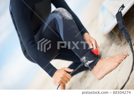 Firmly fastened. Cropped shot of an unrecognizable female surfer attaching her surfboard to her ankle. 88304274