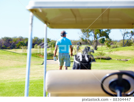 What a great day to be on the golf course.... Rear-view of a golfer walking away with a golf cart in the foreground. What a great day to be on the golf course.... Rear-view of a golfer walking away with a golf cart in the foreground. 88304447
