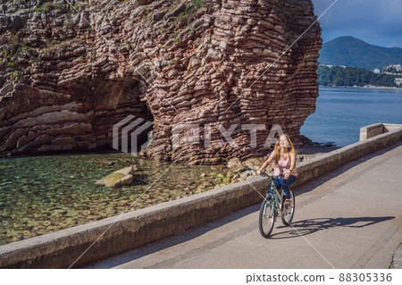Woman tourist on a bicycle explores Budva in Montenegro. Cycling in Montenegro concept Woman tourist on a bicycle explores Budva in Montenegro. Cycling in Montenegro concept 88305336