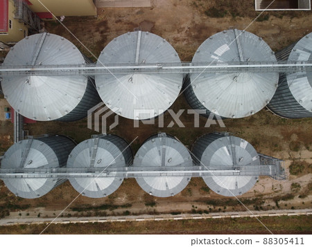 Grain elevator. Metal grain elevator in agricultural zone. Agriculture storage for harvest. Grain elevators on green nature background. Exterior of agricultural factory. Nobody. 88305411