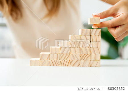 Hand arranging wood cube stacking as stair step shape 88305852