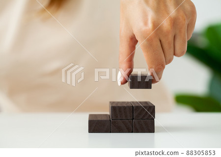 Hand stacking wooden black blocks for in shape of staircase. Hand stacking wooden black blocks for in shape of staircase. 88305853