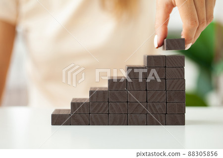 Hand stacking wooden black blocks for in shape of staircase. Hand stacking wooden black blocks for in shape of staircase. 88305856